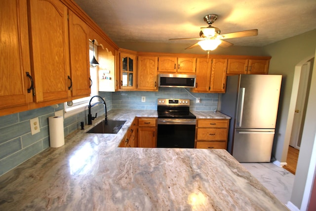 312 Springhurst Dr, Berea, KY 40403 - kitchen with ceiling fan, backsplash, appliances with stainless steel finishes, brown cabinets, and a sink