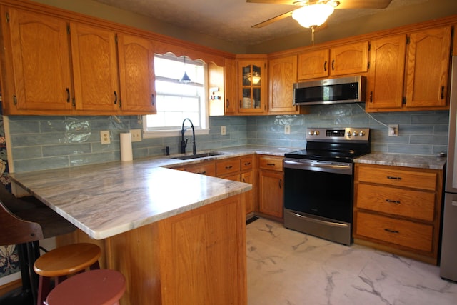 312 Springhurst Dr, Berea, KY 40403 - kitchen featuring appliances with stainless steel finishes, a sink, brown cabinetry, marble finish floor, and a peninsula
