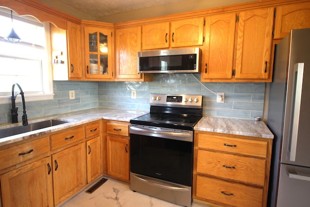 312 Springhurst Dr, Berea, KY 40403 - kitchen featuring backsplash, appliances with stainless steel finishes, brown cabinetry, and a sink