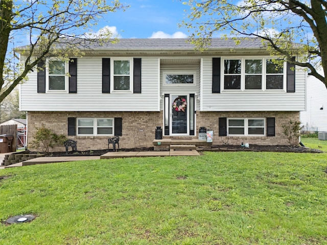 split foyer home featuring brick siding, central AC unit, and a front lawn