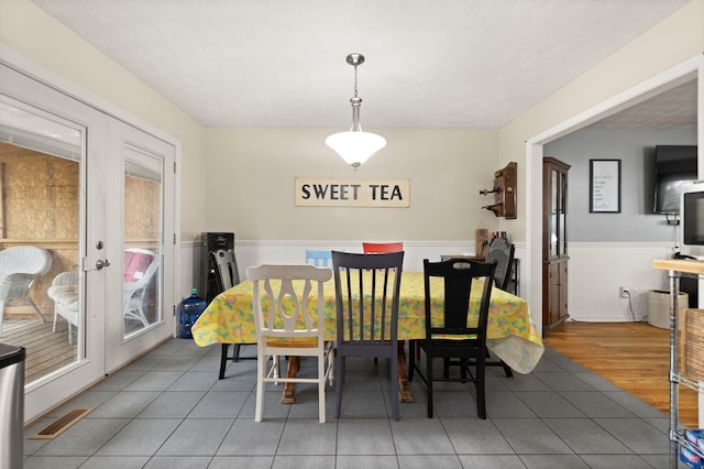 tiled dining area with french doors, wainscoting, and visible vents