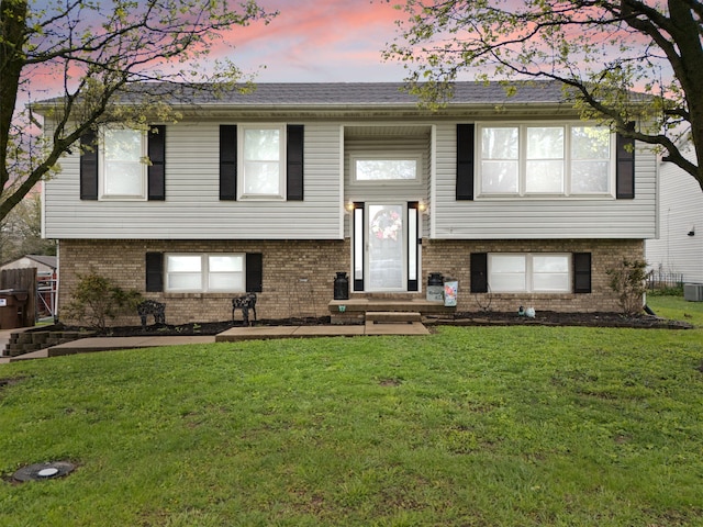 split foyer home with a front yard, central AC, and brick siding