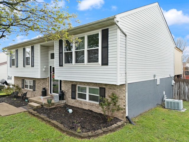 back of house featuring central air condition unit, a lawn, and fence