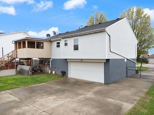back of property with a lawn, stairs, an attached garage, and driveway