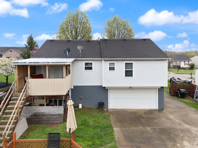 back of property featuring a lawn, a garage, fence, concrete driveway, and stairs