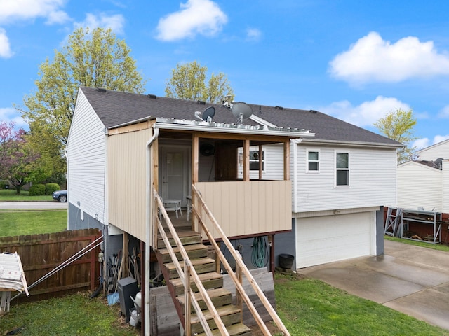back of property with fence, roof with shingles, a garage, stairway, and concrete driveway