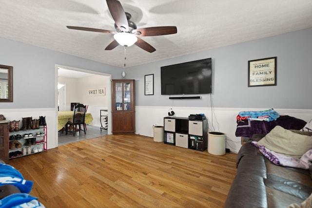 living room featuring ceiling fan, wainscoting, and wood finished floors