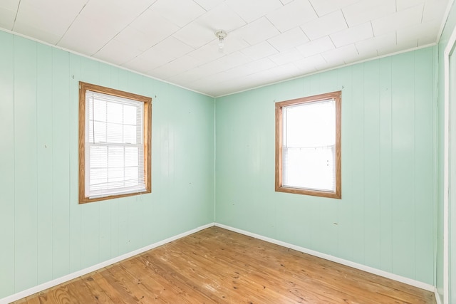 spare room with wooden walls, baseboards, and light wood-style floors