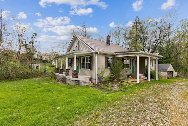 view of side of home featuring a yard, a porch, metal roof, and a chimney