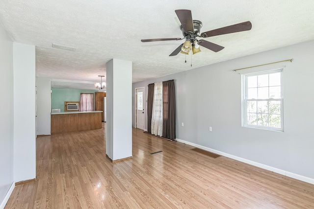 unfurnished living room with visible vents, baseboards, light wood-type flooring, and a textured ceiling