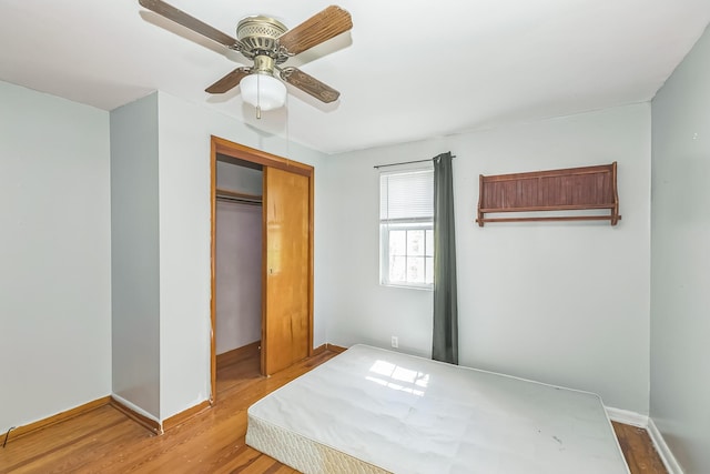 unfurnished bedroom with a closet, baseboards, ceiling fan, and wood finished floors