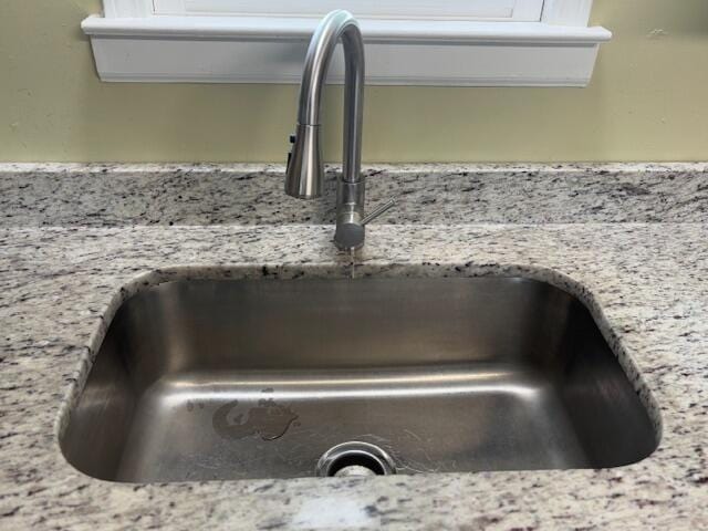 interior details featuring a sink and light stone countertops