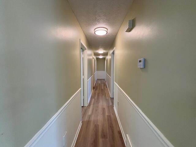 hallway featuring a textured ceiling and wood finished floors