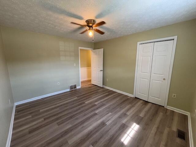 unfurnished bedroom featuring a closet, visible vents, a textured ceiling, and wood finished floors