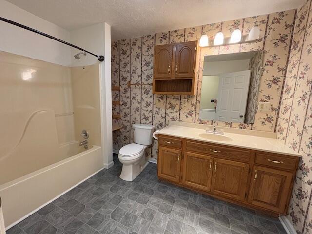 bathroom with vanity, wallpapered walls, shower / tub combination, a textured ceiling, and toilet