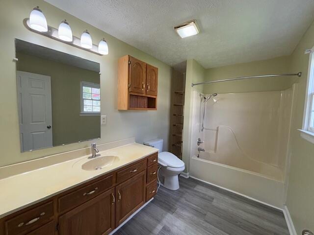 full bathroom with vanity, a textured ceiling, toilet, tub / shower combination, and wood finished floors