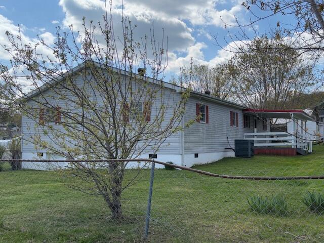 view of side of property featuring crawl space, central air condition unit, fence, and a lawn