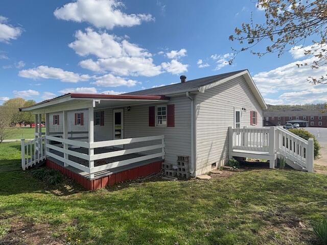back of property with crawl space, a wooden deck, and a lawn
