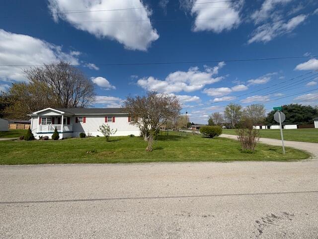 manufactured / mobile home featuring a porch and a front lawn