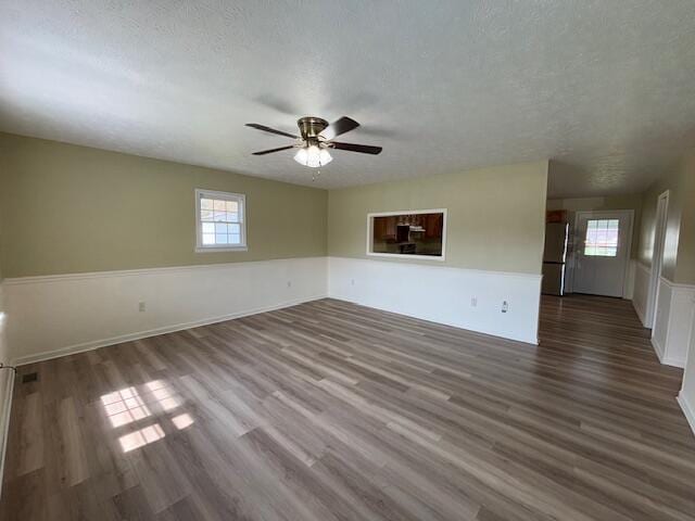 empty room featuring plenty of natural light, a textured ceiling, and wood finished floors
