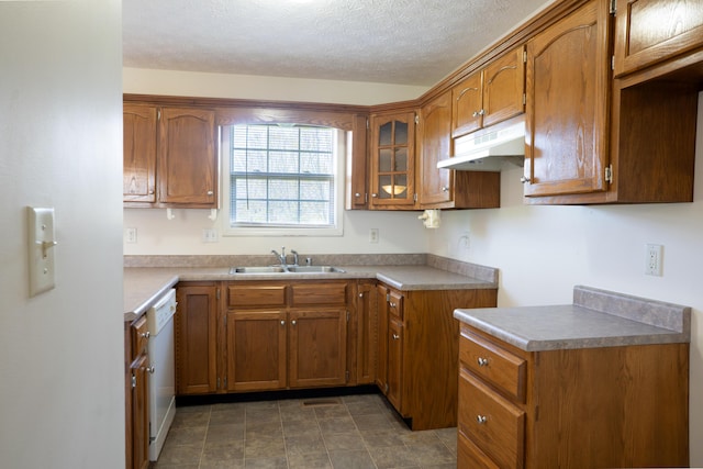 kitchen with a sink, brown cabinetry, glass insert cabinets, dishwasher, and under cabinet range hood
