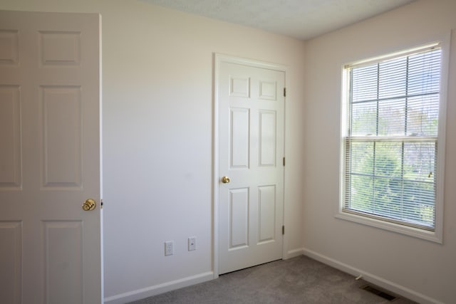 unfurnished bedroom featuring baseboards, visible vents, and carpet