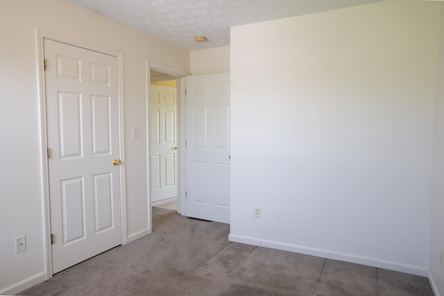 unfurnished bedroom featuring carpet floors, a textured ceiling, and baseboards