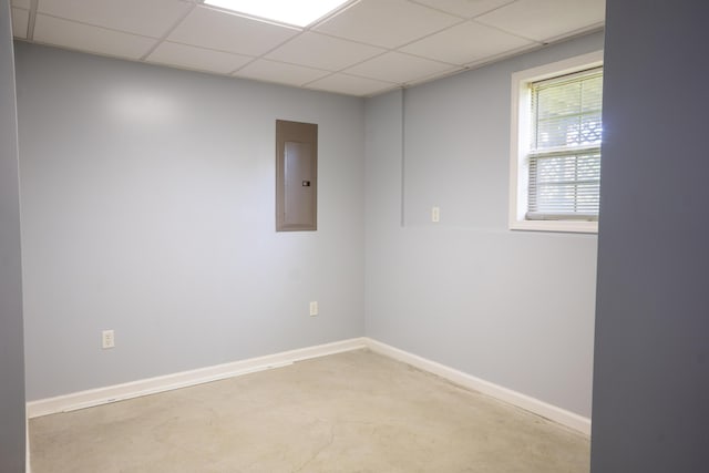 unfurnished room with electric panel, a paneled ceiling, concrete flooring, and baseboards