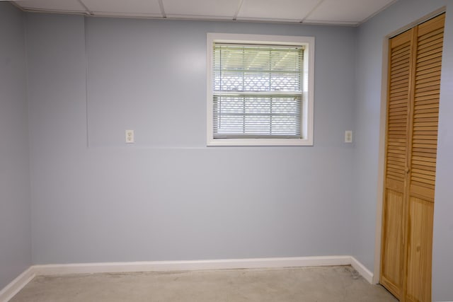unfurnished room with baseboards, a paneled ceiling, and light carpet