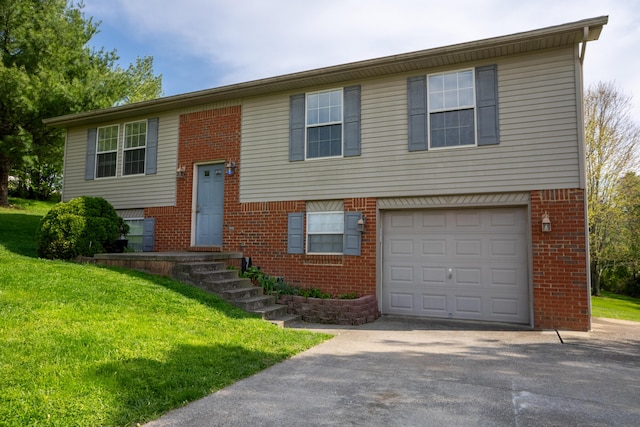 bi-level home featuring driveway, brick siding, a front yard, and a garage
