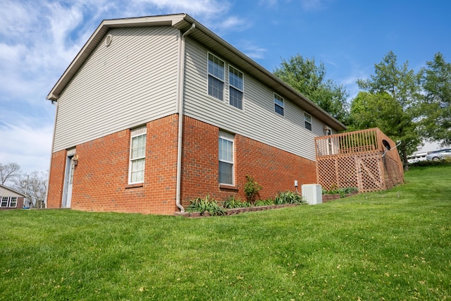 view of side of property featuring central AC, brick siding, and a yard