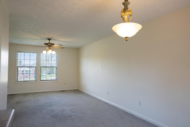 carpeted spare room with a textured ceiling, a ceiling fan, and baseboards