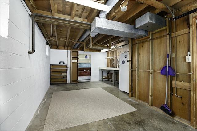 unfinished below grade area featuring freestanding refrigerator and concrete block wall