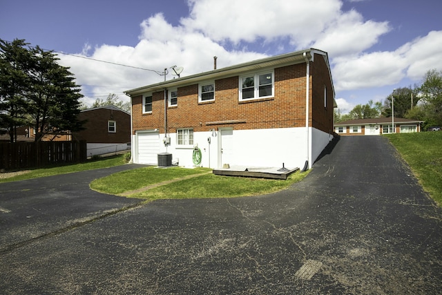 back of property with a garage, central AC, fence, brick siding, and driveway
