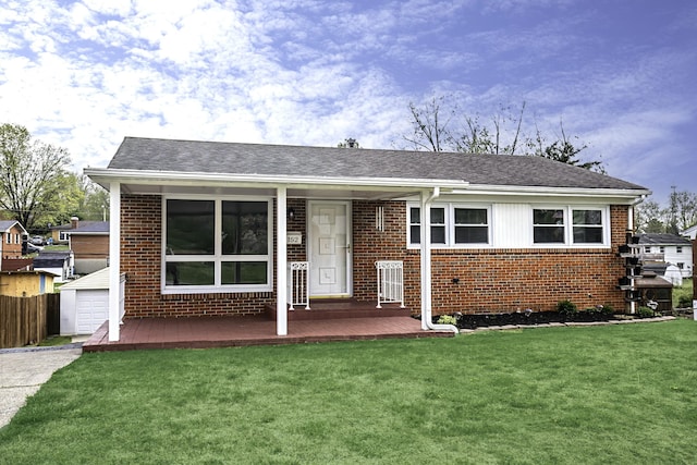 single story home featuring brick siding, a front yard, fence, and roof with shingles