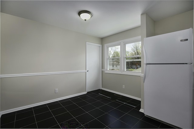 unfurnished dining area featuring dark tile patterned flooring and baseboards