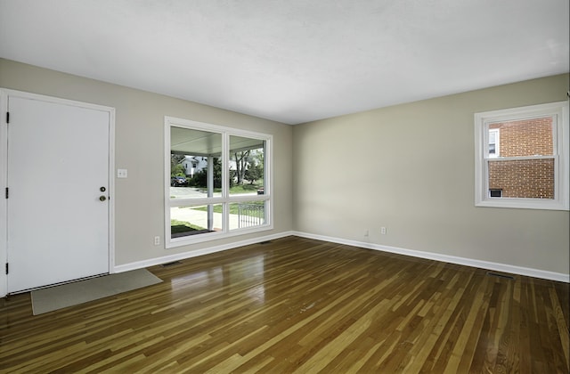 unfurnished living room featuring wood finished floors, baseboards, visible vents, and a wealth of natural light