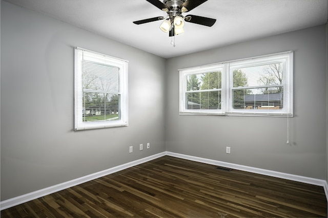 empty room with a ceiling fan, baseboards, dark wood finished floors, and visible vents