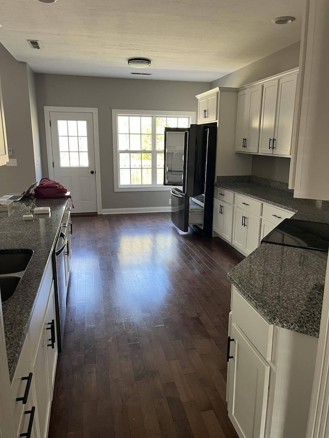 kitchen featuring dark wood-type flooring, dark stone countertops, and white cabinets