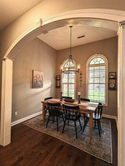 dining space with arched walkways, wood finished floors, baseboards, and visible vents
