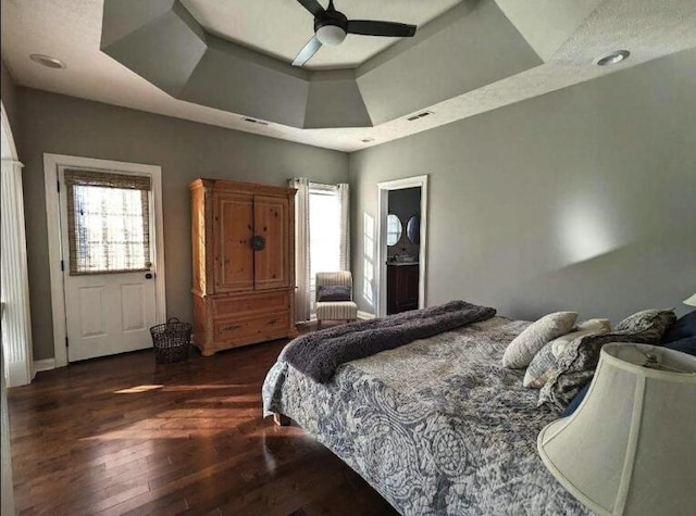 bedroom featuring visible vents, ceiling fan, a raised ceiling, and wood finished floors