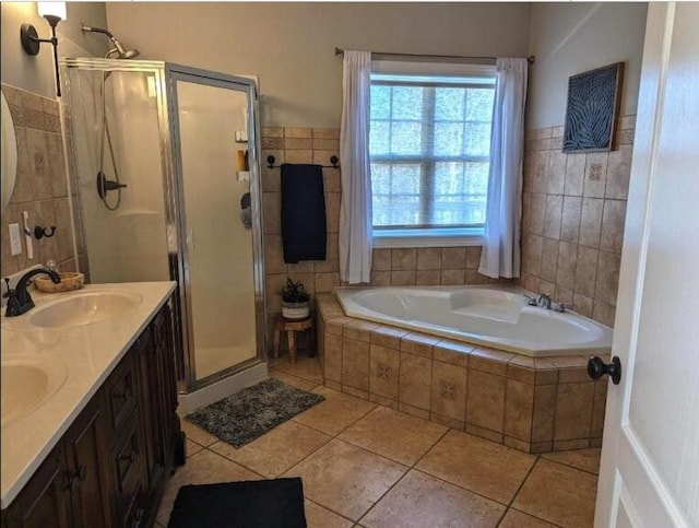 full bathroom featuring a garden tub, a sink, a stall shower, double vanity, and tile patterned floors