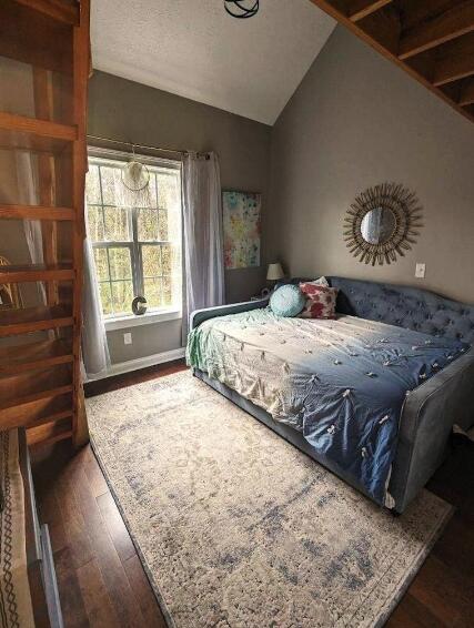 bedroom featuring wood finished floors and lofted ceiling