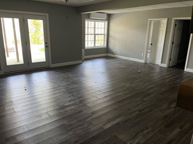 unfurnished room featuring dark wood-type flooring, a wall unit AC, and baseboards