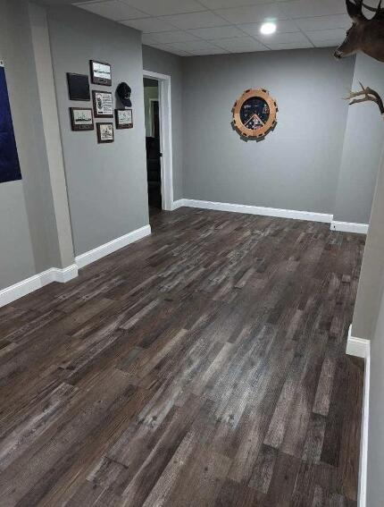 basement featuring dark wood finished floors, baseboards, and a drop ceiling