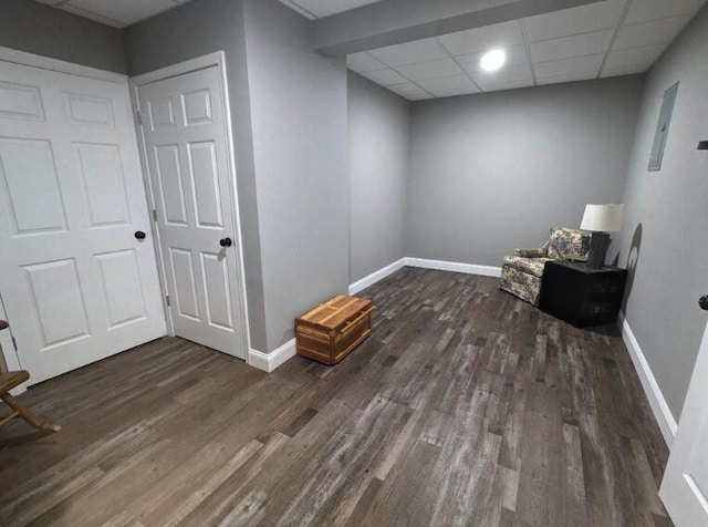 finished basement featuring a paneled ceiling, baseboards, and wood finished floors