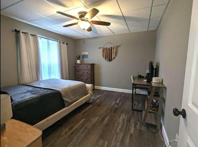 bedroom with a paneled ceiling, wood finished floors, baseboards, and a ceiling fan