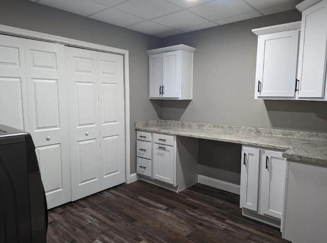 unfurnished office with a paneled ceiling and dark wood finished floors