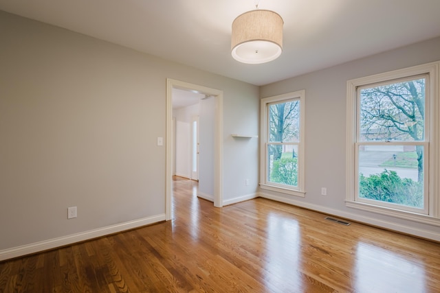 empty room featuring baseboards, visible vents, and wood finished floors