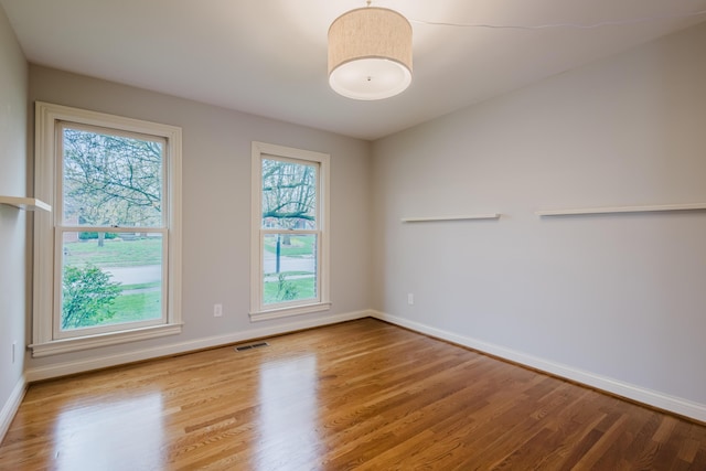 empty room featuring baseboards, visible vents, and wood finished floors